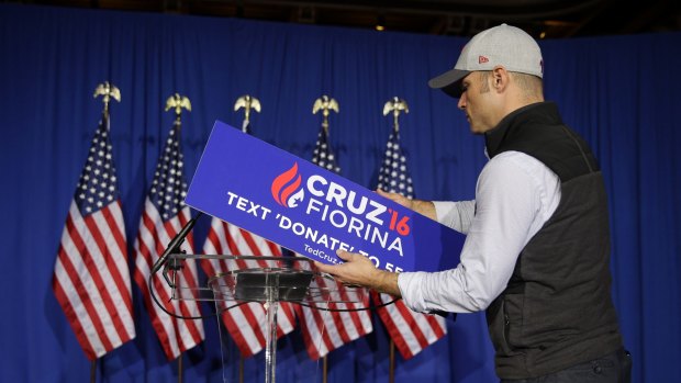 A worker for former Republican presidential candidate Senator Ted Cruz removes the campaign sign from the podium following a primary night campaign event in Indianapolis.