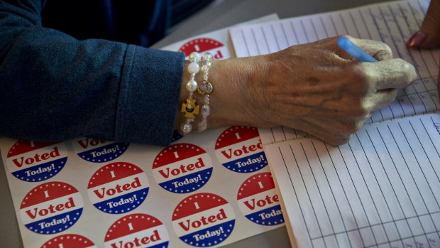 A majority inspector checks-in a resident to vote next to "I Voted Today" stickers at a residential garage polling location in Philadelphia, Pennsylvania.