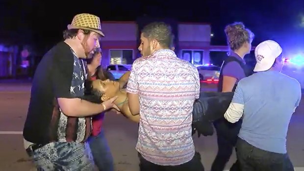 An injured person is escorted out of the Pulse nightclub in Orlando after being shot.