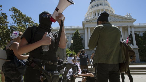 Members of the group called ANTIFA Sacramento (Anti-Fascism Action) try to light a flag on fire as they stage a counter-protest against skinheads at the California state Capitol in Sacramento, California.