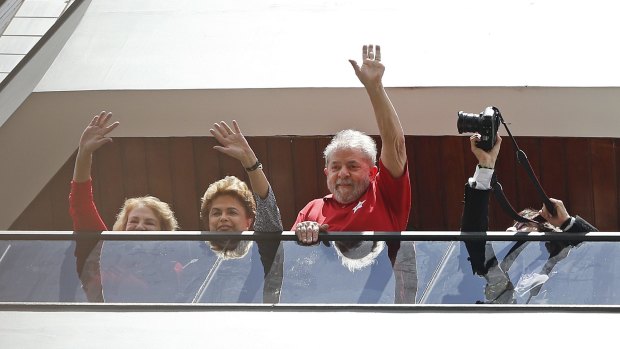 Brazil's former president Luiz Inacio Lula da Silva, right, with President Dilma Rousseff, centre, and Lula's wife, Marisa Leticia, left, wave to supporters from the balcony of his home on Saturday.