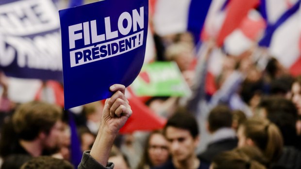 A supporter holds up a sign during an election campaign meeting for France's presidential candidate Francois Fillon.