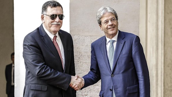 Italian Premier Paolo Gentiloni, right, welcomes Libyan Prime Minister Fayez al-Sarraj in the courtyard of Chigi Palace in Rome.