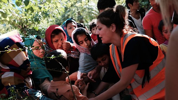 Food and water are given to migrants living in a park in Athens.