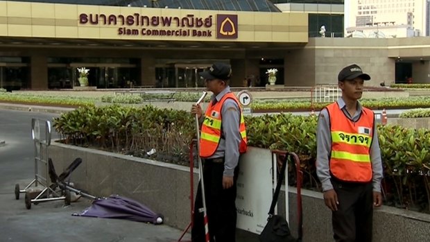 Security guards stand outside Siam Commercial Bank's headquarters in Bangkok.