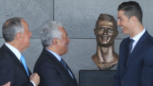 Football superstar Cristiano Ronaldo stands next to the dubious statue.