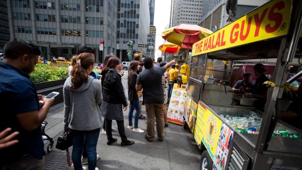 Customers queue at The Halal Guys' food cart on West 53rd Street and 6th Avenue.