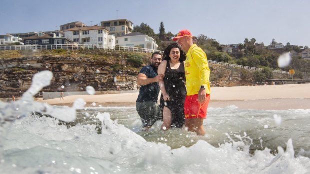 Volunteer lifesaver Paul Borrud talks to new Syrian migrants Alaa (Alan) Alnseer and his sister Lama at a beach safety day for new migrants at Tamarama.