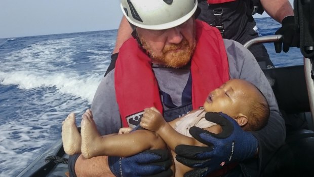 A Sea-Watch humanitarian organisation crew member holds a drowned migrant baby, during a rescue operation off the coasts of Libya. 