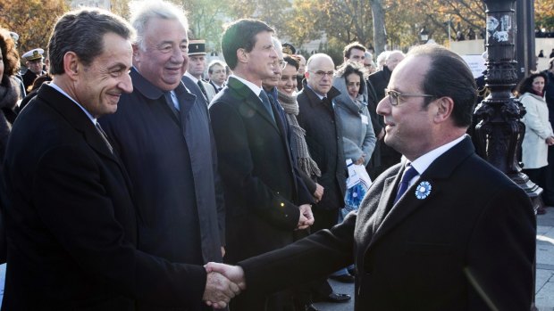 French President Francois Hollande, right, shakes hand with former French President Nicolas Sarkozy during the Armistice Day ceremonies in Paris.