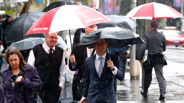 Pedestrians take cover from the rain in Sydney on Thursday.