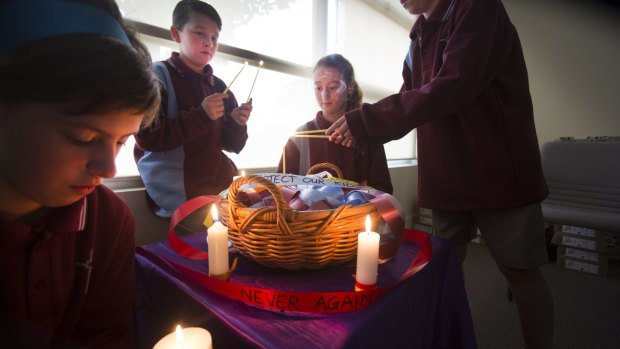 Students of St Alipius Parish School light candles to acknowledge child abuse within the Catholic Church.