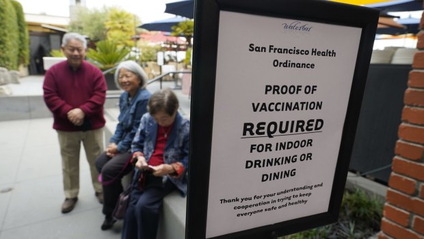 Peopel wait to have their vaccination records checked before entering a restaurant in San Francisco.