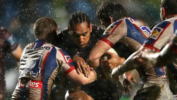 Wet and wild: Martin Taupau drives into the Newcastle defence on Friday night.