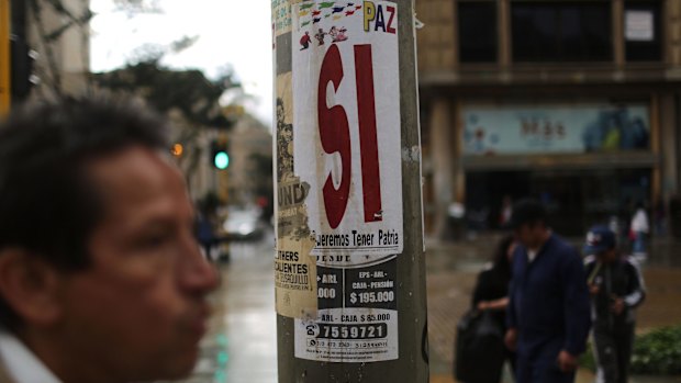 A man walks past a campaign poster for a 'Yes' vote, written 'Si' in Spanish, on the peace referendum in Bogota.