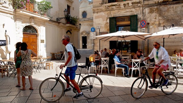 Tourists on bicycles explore the streets and squares of Lecce in Italy's southern region of Puglia.