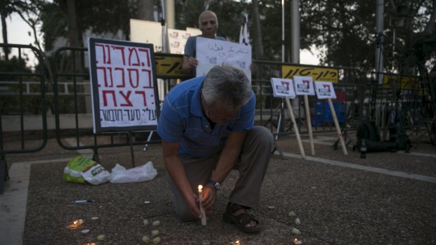 A man lights a candle in memory of  Ali Dawabshe at Rabin Square in Tel Aviv.
