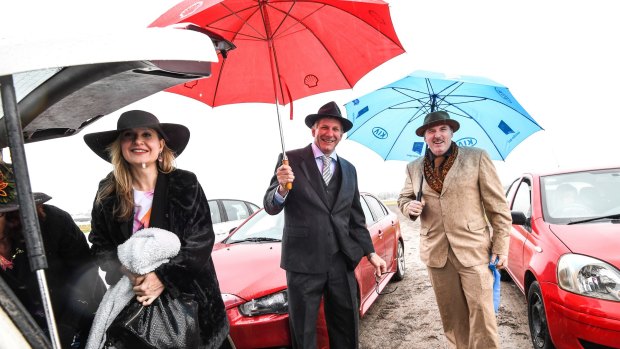 The muddy carpark doesn't dampen these punters' enthusiasm at Flemington racecourse.