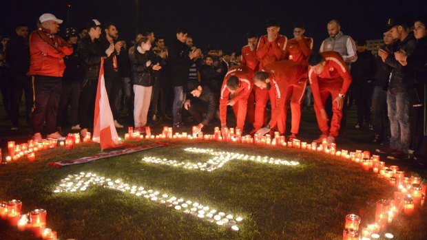 Dinamo Bucharest players light candles along with supporters after teammate Patrick Ekeng's death.