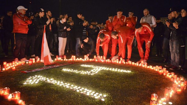 Dinamo Bucharest players light candles along with supporters after teammate Patrick Ekeng's death.