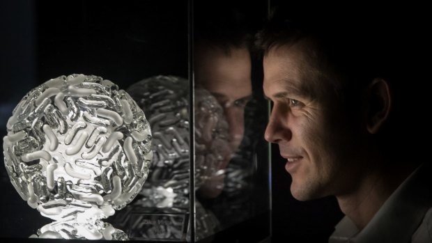 Artist Luke Jerram looks at a jewel-like sculpture of the Zika virus in the Glass Microbiology exhibition in Bristol, England.