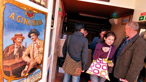 Customers grab a ginjinha, Lisbon's sour cherry liquor that was invented as a cough medicine.