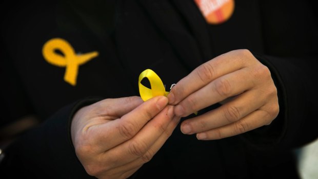 A supporter of Junts per Catalunya or Together for Catalonia makes a yellow ribbon in support of Catalonian politicians who have been jailed.