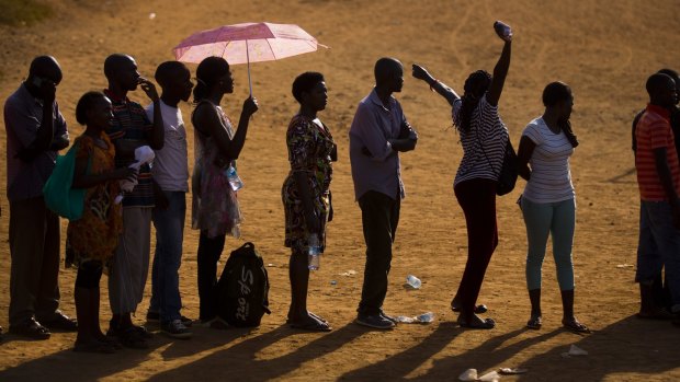 A voter stretches her arms as she and other Ugandans wait to vote at sunset in the capital Kampala.