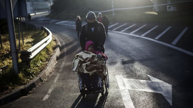 An Iraqi migrant pushes his son's wheelchair on their way to Austria, at the Slovenian Austrian border near Sentijl, last weekend.
