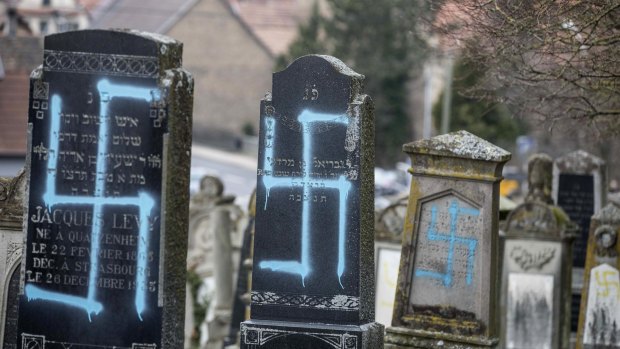 Vandalized tombs with tagged swastikas are pictured in the Jewish cemetery of Quatzenheim, in eastern France, on Tuesday, February 19, 2019.