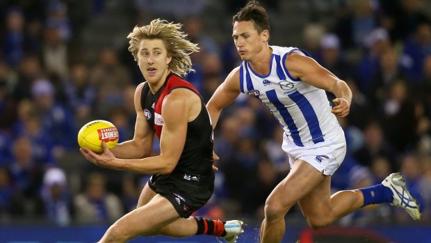 Dyson Heppell (left) is tackled by Ben Jacobs of the Kangaroos. Heppell has said he would be happy to assume the Essendon captaincy permanently.