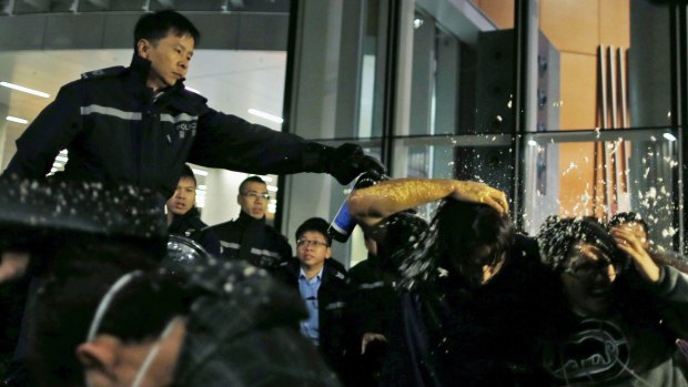 Taking a hard line: Pro-democracy protesters are pepper sprayed by a policeman as they try to break into the Legislative Council in Hong Kong.  