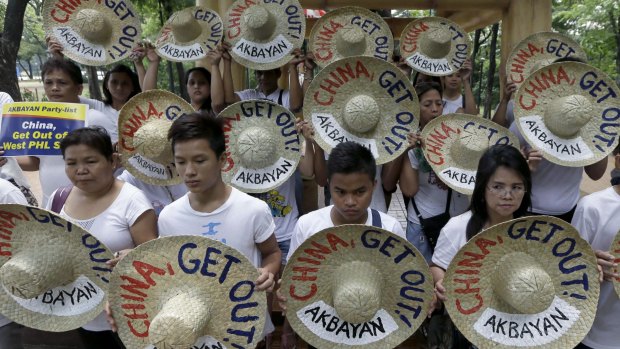 Protesters display traditional hats with anti-China messages as a Chinese dragon dance is performed during a protest on Thursday at a park in Quezon city north-east of Manila.