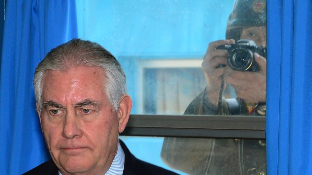 A North Korean soldier, right, tries to take a photograph through a window while US Secretary of State Rex Tillerson visits the UN Command Military Armistice Commission meeting room on Friday.