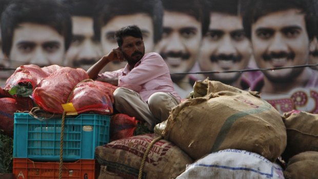 A man rests on vegetables being transported by truck in India's southern city of Hyderabad.