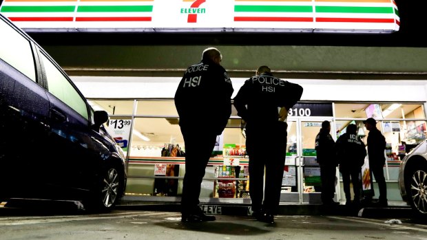 US Immigration and Customs Enforcement agents serve an employment audit notice at a 7-Eleven convenience store in Los Angeles. 