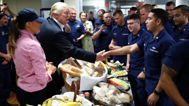 President Donald Trump, with first lady Melania Trump, greets and hands out sandwiches to US Coast Guard members.