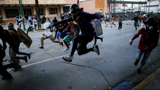 Anti-government protesters run from advancing Venezuelan Bolivarian National Guard officers on the first day of a 48-hour general strike in protest of government plans to rewrite the constitution, in Caracas, Venezuela.