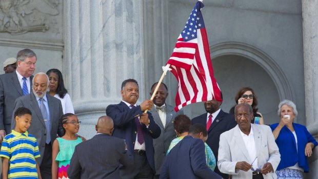 Reverend Jesse Jackson waves an American flag before the Confederate battle flag is taken down from the statehouse.