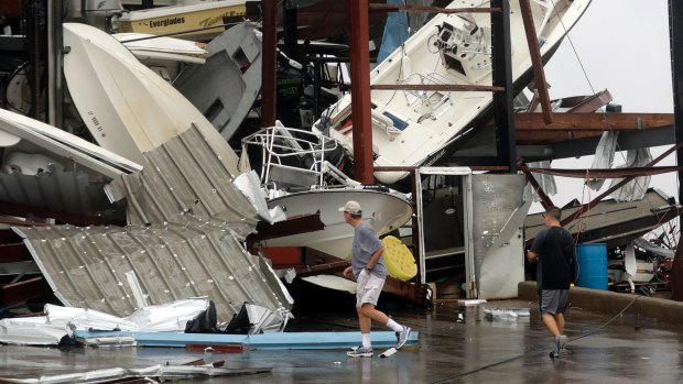 People walk past a boat storage facility that was damaged by Hurricane Harvey in Rockport, Texas. 