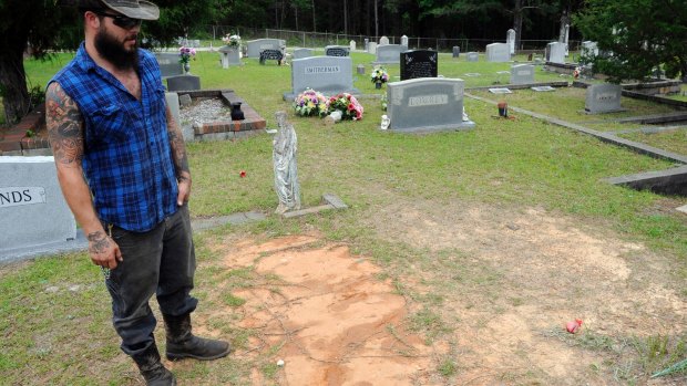 Tyler Goodson of the podcast <i>S-Town</i> stands at the grave of his  friend John B McLemore, 
