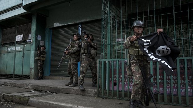 A soldier carries an Islamic State flag seized while clearing a street of militants in Marawi city, southern Philippines. 