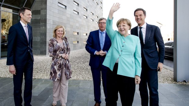 German Chancellor Angela Merkel waves as she arrives with Dutch Prime Minister Mark Rutte, right, for a visit to chip manufacturer ASML in Veldhoven, near Eindhoven, Netherlands last week.