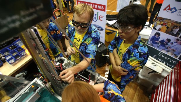 Robots kicking goals: Thunder's pit crew make repairs after a match.