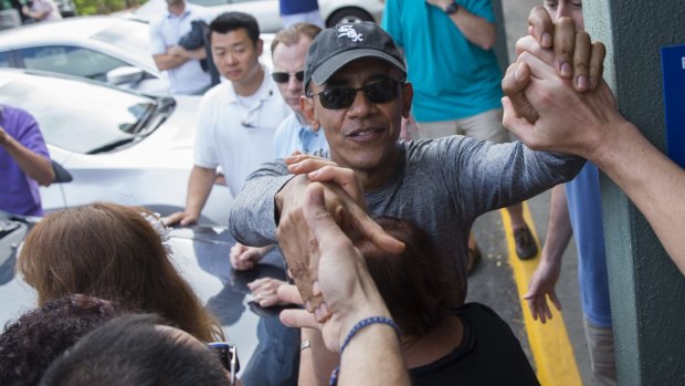 President Barack Obama shakes hands with bystanders during a visit to Island Snow, a store for athletic clothing that has a shave-ice machine, during his family holiday in Hawaii on Sunday.