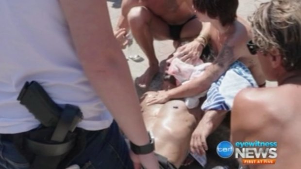 Beachgoers hold a towel to the head of a man who was attacked at Bondi on Thursday.
