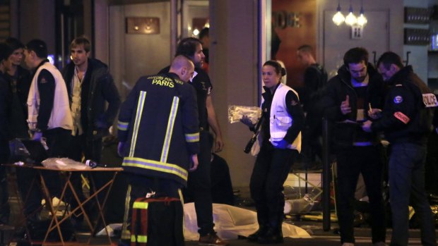 Police officers and rescue workers gather around a victim outside a Paris restaurant on Friday