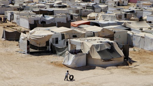 A Syrian refugee boy plays with a tyre at Zaatari refugee camp, in Mafraq, Jordan. 