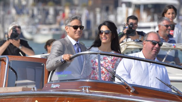 George Clooney and his wife Amal Alamuddin stand on a taxi boat in Venice.