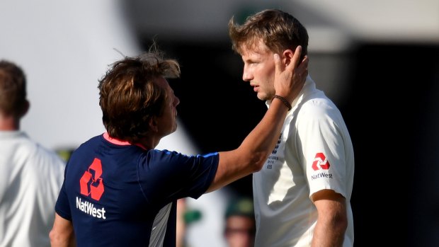 Joe Root is checked out by medical staff after being hit in the head.